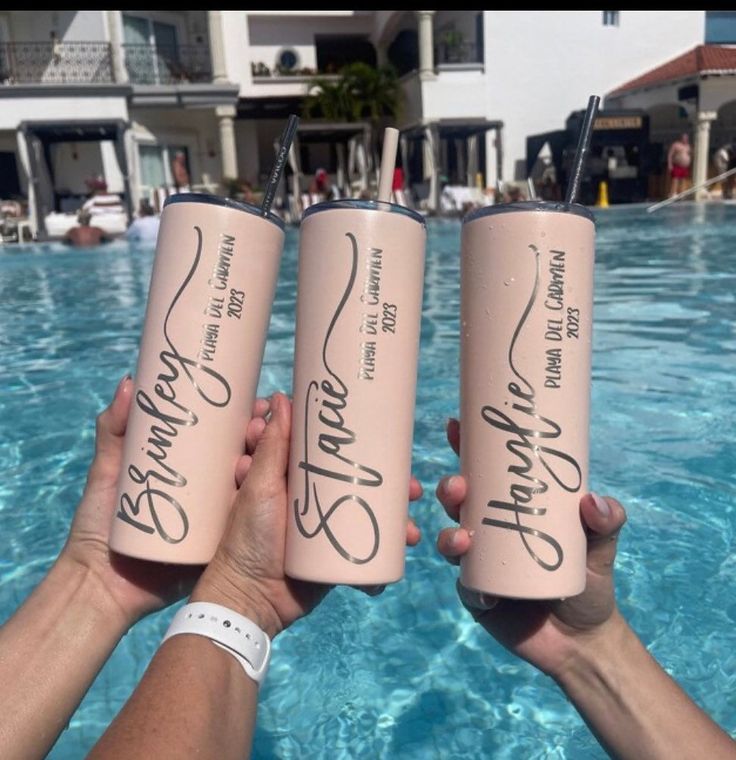 three people holding up pink water bottles in front of a swimming pool with the words stay strong written on them