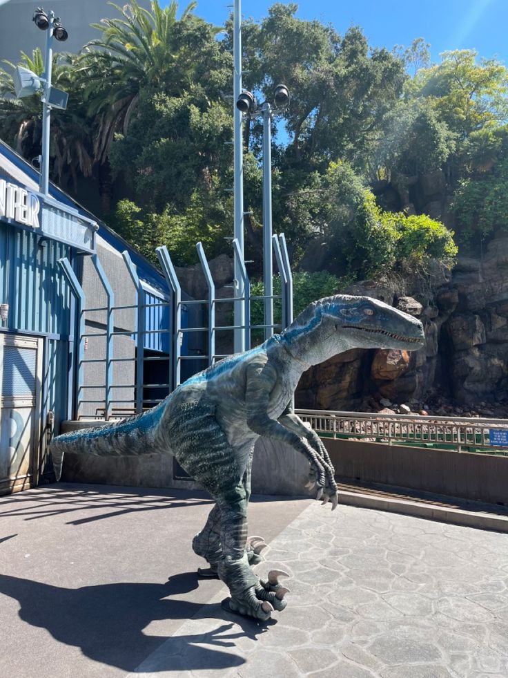 a dinosaur statue in front of a blue building