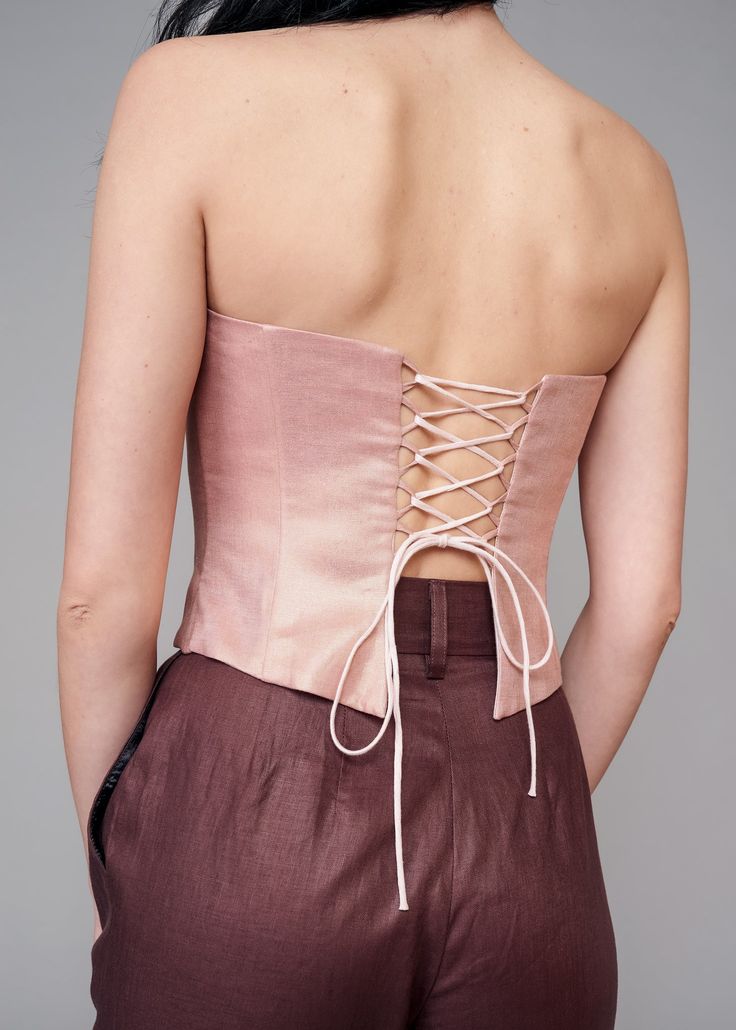 Elevate your style with the IRA LYSA Pink Metallic Corset. Stand out in the crowd while not compromising on comfort. The pink is delicate but the corset shape keeps this piece chic and high-fashion. * Made with corset boning* Air loops and long spaghetti strap on the back* Wave bottom finish Material: 100% European linen Handmade. Always. Luxury Bustier Corset With Bust Darts, Chic Sleeveless Corset With Lace-up Back, Spring Party Corset With Boning, Pink Strapless Chic Corset Dress, Feminine Fitted Pink Corset, Pink Sleeveless Corset With Built-in Bra, Spring Fitted Boned Bodice Corset, Strapless Satin Summer Corset, Elegant Fitted Pink Corset