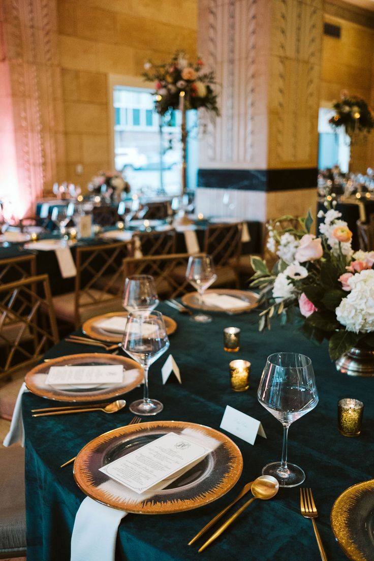 the table is set with place settings and flowers on it for an elegant dinner party