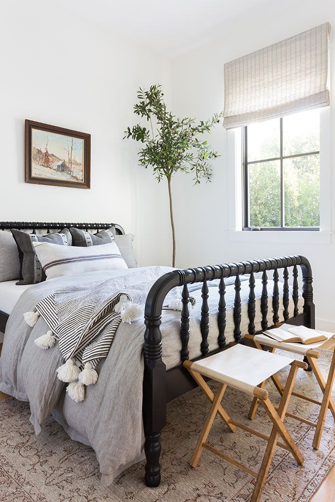 a bedroom with a bed, two chairs and a potted plant