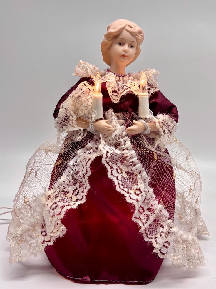 a figurine with two candles in its hands and a red dress on it