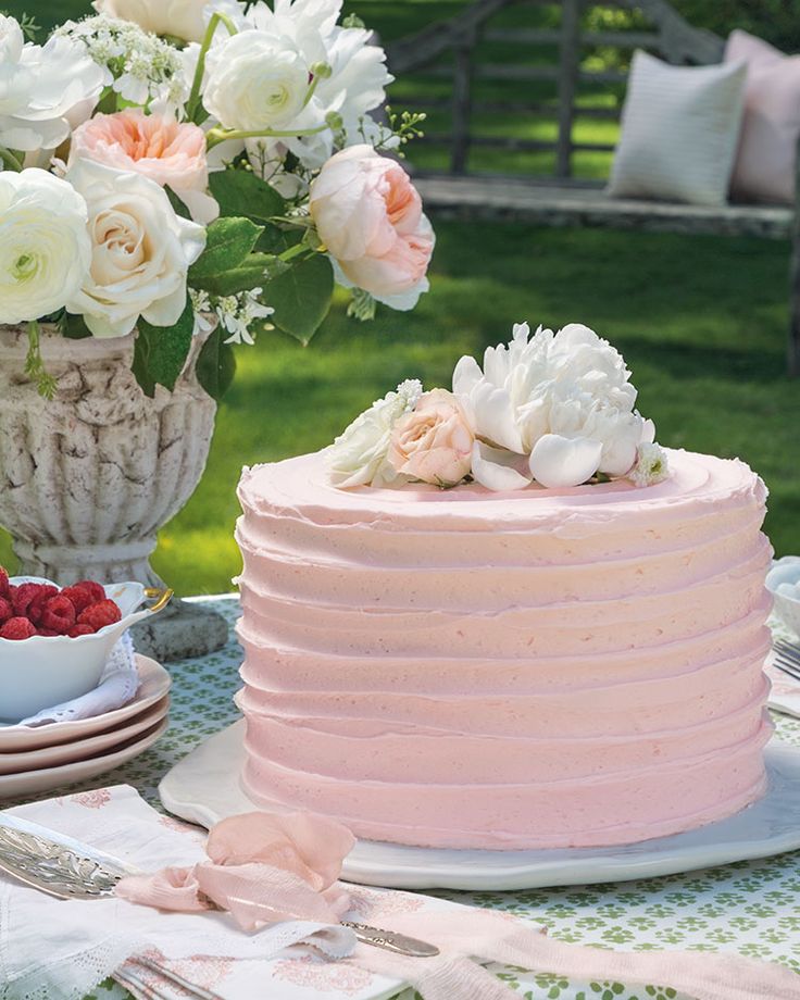 a pink cake sitting on top of a table next to a bowl of strawberries