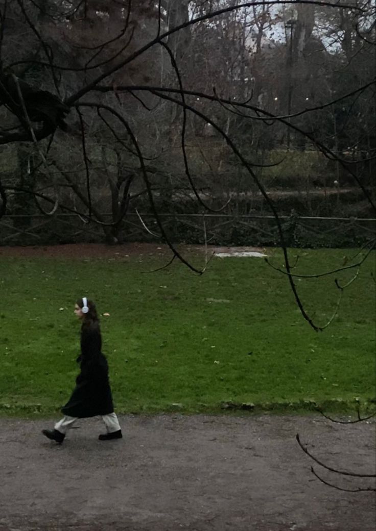 a woman walking across a lush green park