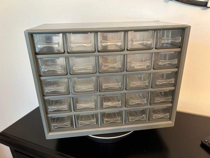 a black table topped with drawers filled with clear plastic containers on top of each other