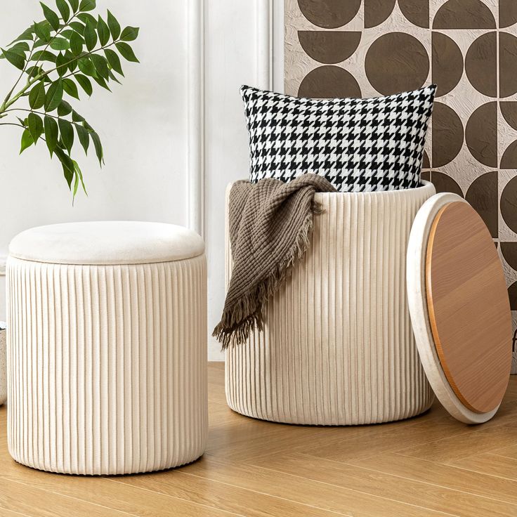 two white stools sitting on top of a wooden floor next to a potted plant