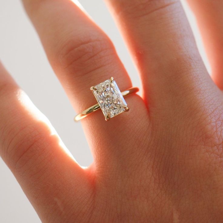 a woman's hand with a diamond ring on top of her finger, showing the center stone