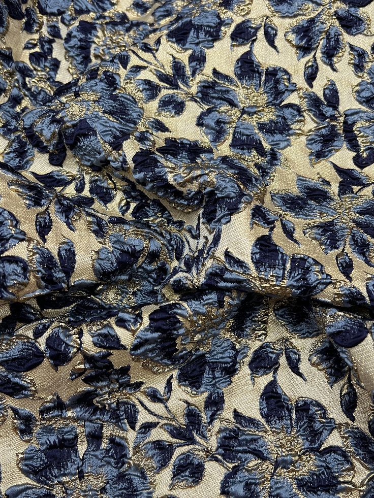 a blue and beige floral print fabric with black flowers on it, in the background