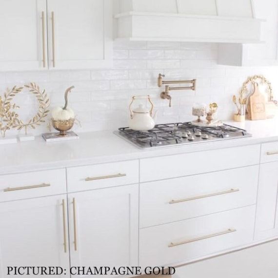 a kitchen with white cabinets and gold accents