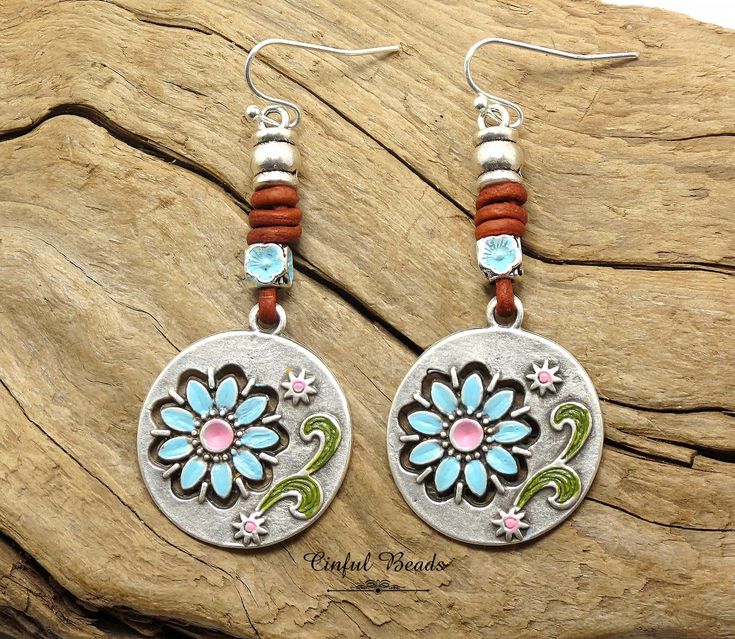 Add a touch of bohemian charm to your outfit with these unique boho leather earrings. Each earring features a hand-painted flower pendant, complemented by a matching hand-painted flower bead and decorative leather barrel knots. You even have the option to choose your preferred earwires for a personalized touch.  These earrings are a stylish and versatile addition to your jewelry collection, perfect for any occasion. 𝐋𝐄𝐍𝐆𝐓𝐇: 2 1/2" with hook wires. Kidney wires will add about 1". 𝐖𝐈𝐃𝐓𝐇 Bohemian Brown Flower Jewelry, Multicolor Bohemian Earrings With Flower Charm, Bohemian Multicolor Earrings With Flower Charm, Adjustable Bohemian Drop Flower Earrings, Spring Bohemian Turquoise Jewelry, Whimsical Adjustable Flower Charm Earrings, Bohemian Brown Dangle Flower Earrings, Hand Painted Jewelry For Spring, Bohemian Brown Flower Earrings