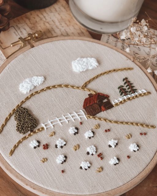 a close up of a embroidery on a table with a candle and some other items