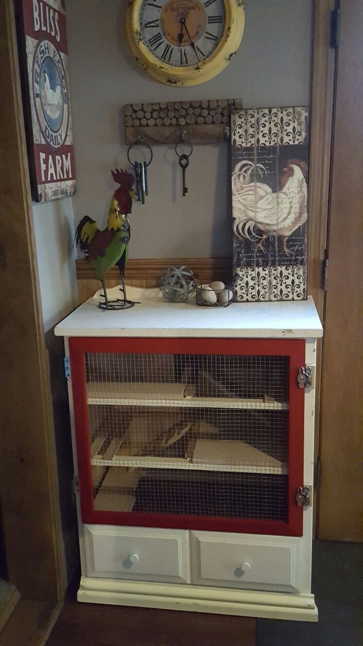 a red and white hutch with a chicken in it's cage next to a clock