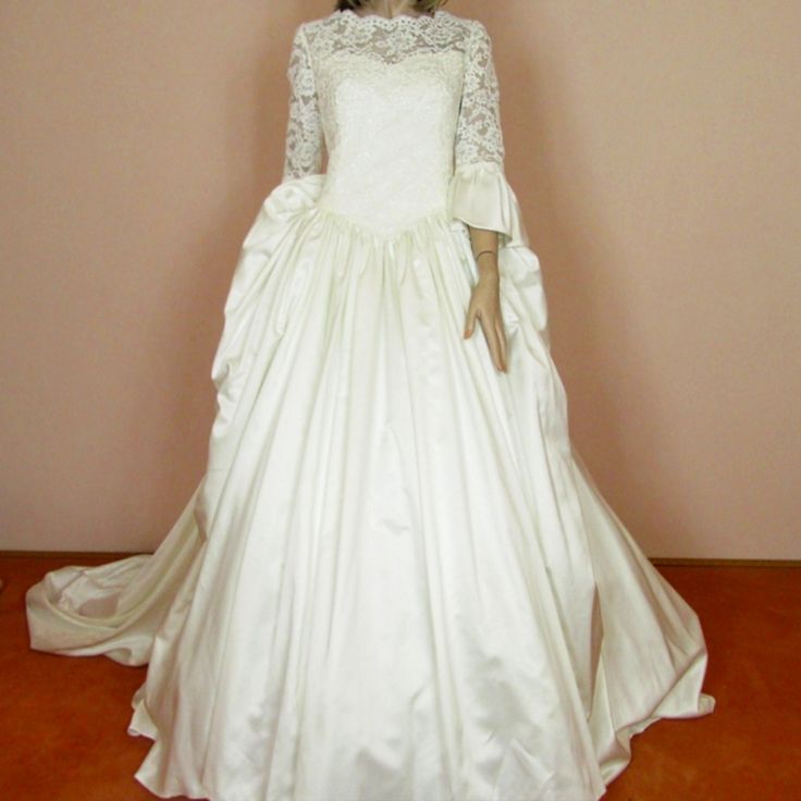 a woman in a white wedding dress standing next to a wall