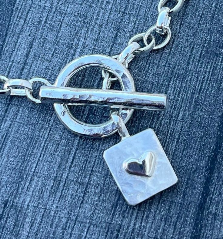 This Sterling Silver fob bracelet features a hammered rectangle charm with silver heart detail. The medium belcher link, bracelet length is approx: 8.5" and it assembles together with the hammered toggle. If you need a different length please leave a note or message.  Matching necklace available as well as a gold heart option. Heart-shaped Charm Bracelet With Toggle Clasp As Gift, Heart Charm Bracelet With Toggle Clasp For Gift, Elegant Heart Bracelet With Toggle Clasp For Gift, Silver Charm Bracelet With Rectangular Links, Rectangular Link Bracelet With Spring Ring Clasp As Gift, Gift Rectangular Link Bracelet With Spring Ring Clasp, Metal Charm Bracelet With Sterling Silver Clasp As Gift, Sterling Silver Heart Charm Bracelet For Gift, Silver Heart Bracelet With Toggle Clasp