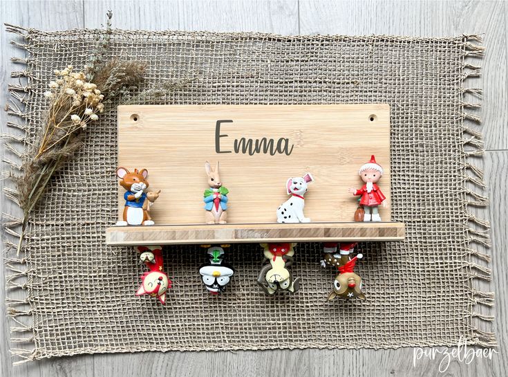 small figurines sitting on top of a wooden shelf with the word emma