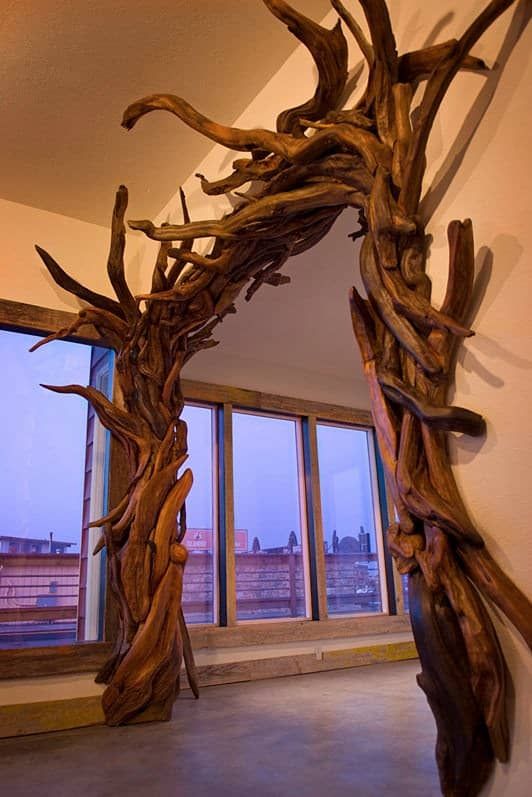 a wooden arch made out of branches in an empty room with large windows behind it