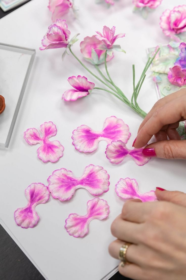 a woman is painting flowers with acrylic paint on the table next to it