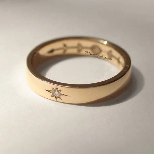 a gold wedding band with a star on the side and two diamonds in the middle