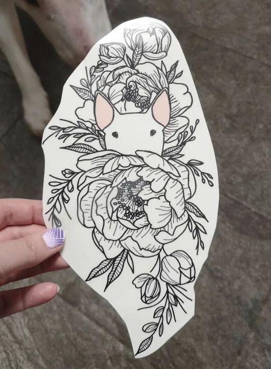 a person holding up a sticker with an animal on it's face and flowers