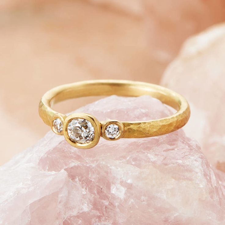 a gold ring with two diamonds sitting on top of a rock