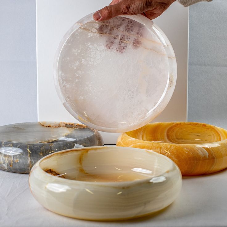 a person is holding a bowl with ice in it next to other bowls on the table