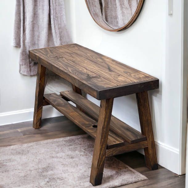 a wooden bench sitting in front of a wall with a mirror on top of it