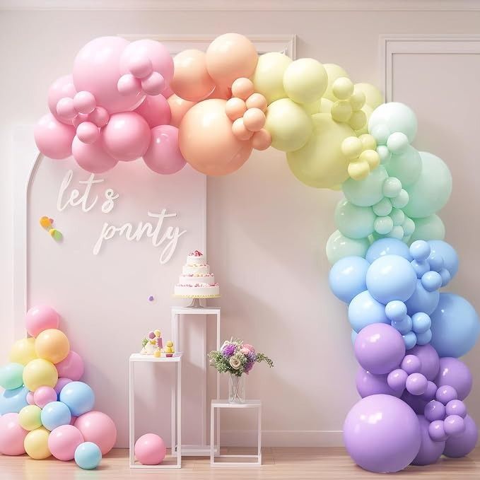 there is a rainbow colored balloon arch in the room that says let's party