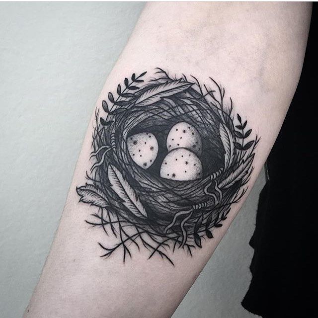 a bird's nest with three eggs tattoo on the left upper half of the arm