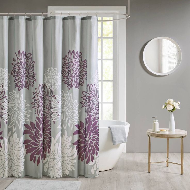 a white and purple shower curtain with flowers on it next to a bathtub in a bathroom