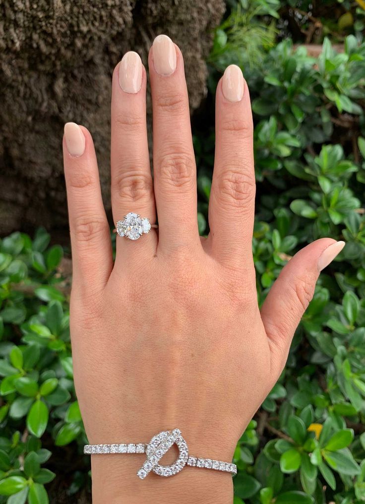 a woman's hand with a diamond ring on her left wrist and an oval shaped diamond band around the middle finger