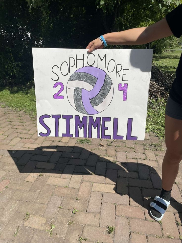 a woman holding up a sign that says sophromore 2 1 stimmell