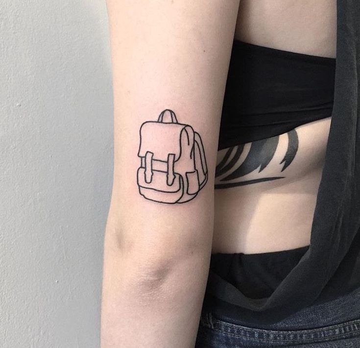 a black and white photo of a woman's arm with a backpack tattoo on it