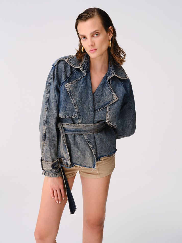 Step into a realm of timeless elegance with the Reckless Cropped Fit Denim Trench Coat. Made from 100% organic cotton, this coat combines sustainability with style, offering a chic cropped fit that complements all body types. Featuring eye-catching epaulettes on the shoulders, practical pockets, and adjustable belt and buckle details on the waist and wrists, this piece is as functional as it is fashionable. FABRIC: -100% Organic cotton. Chic Relaxed Fit Denim Blue Outerwear, Chic Denim Blue Cotton Outerwear, Chic Belted Cotton Outerwear, Oversized Chic Denim Jacket In Cotton, Oversized Chic Cotton Denim Jacket, Chic Denim Blue Cotton Denim Jacket, Chic Oversized Cotton Denim Jacket, Chic Oversized Denim Blue Denim Jacket, Relaxed Fit Washed Outerwear In Recycled Denim