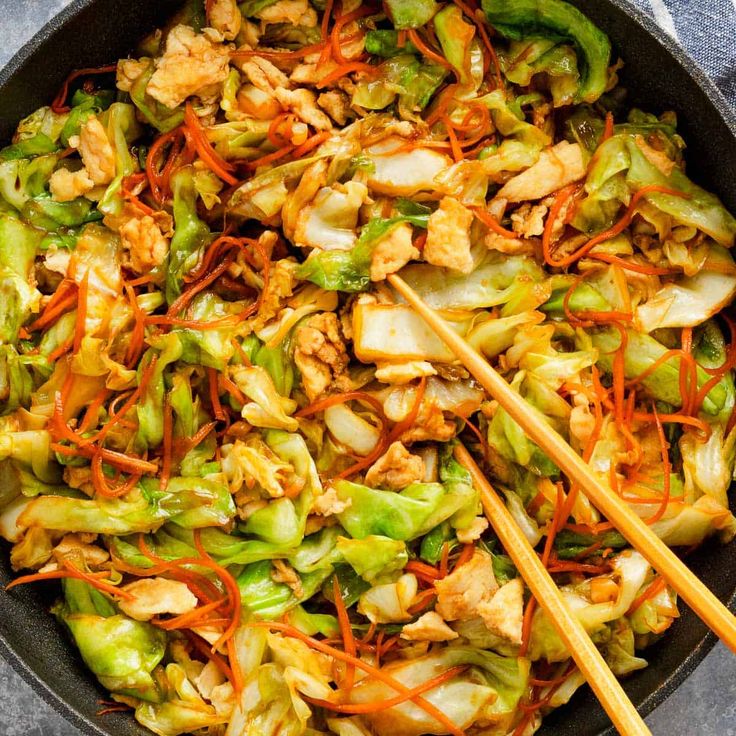 a wok filled with stir fry vegetables and chopsticks