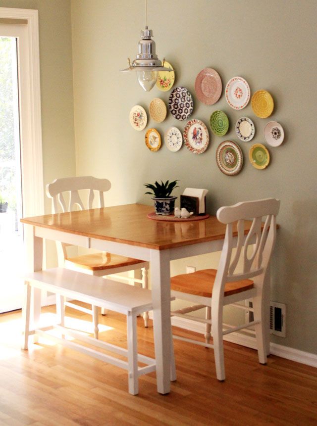 a dining room table with two chairs and plates on the wall