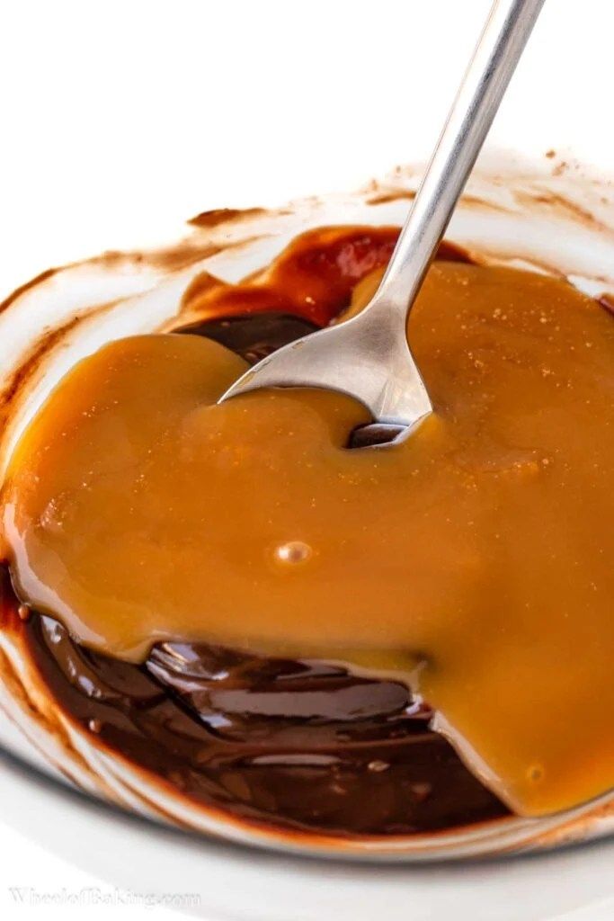 a spoon is being used to stir caramel sauce