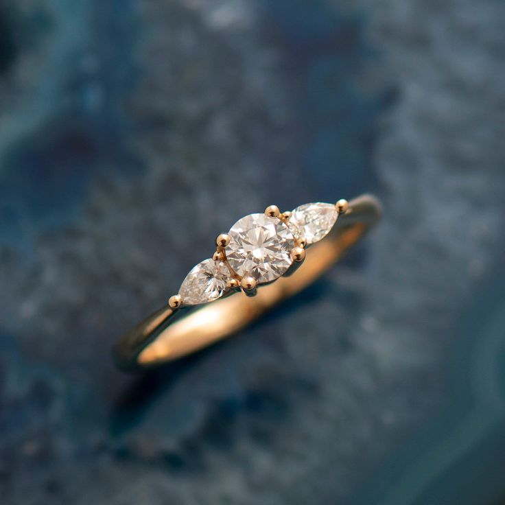 three stone diamond ring sitting on top of a blue surface