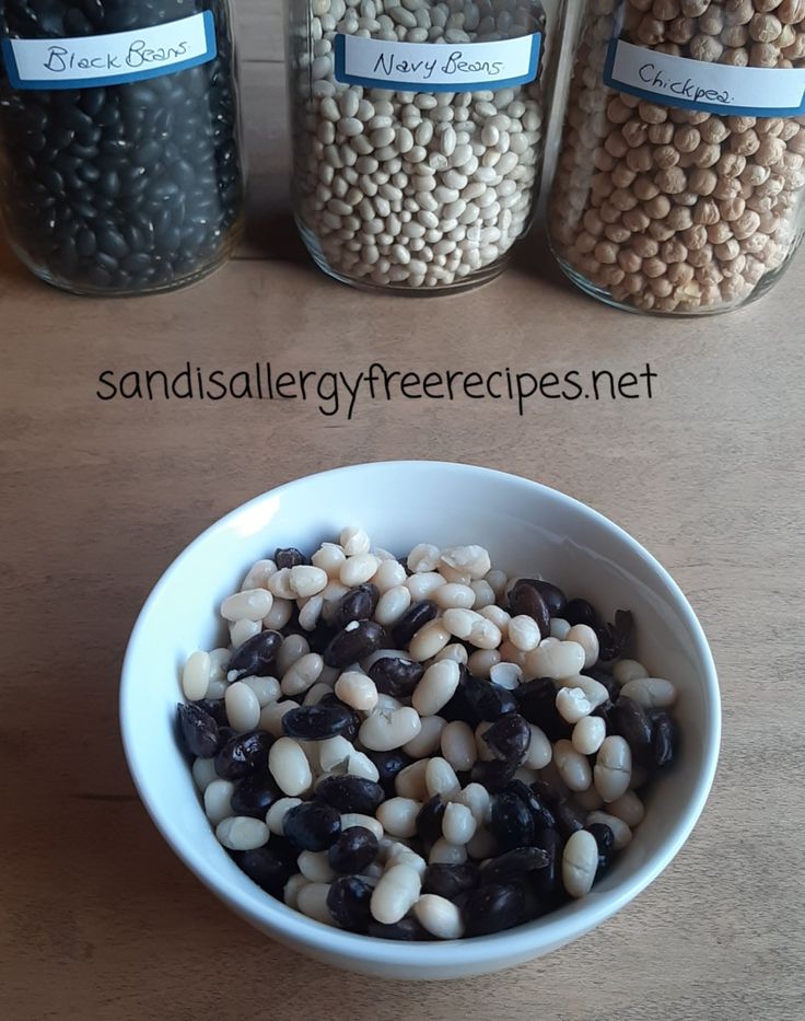 three jars filled with beans next to each other on top of a wooden countertop