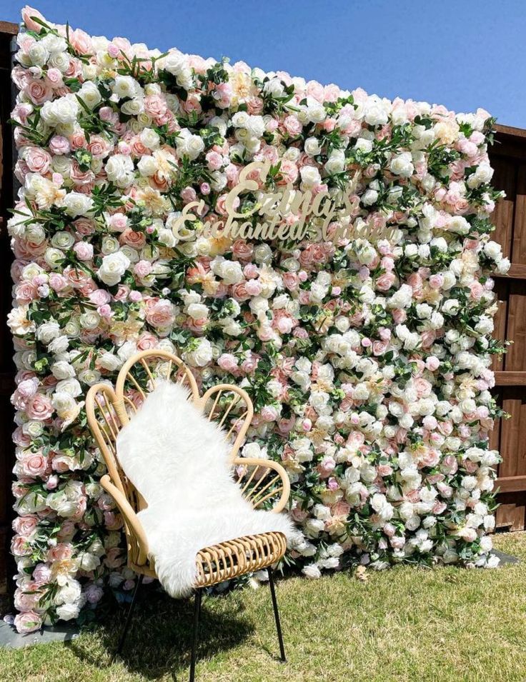 a chair sitting in front of a flower wall with flowers on it's side