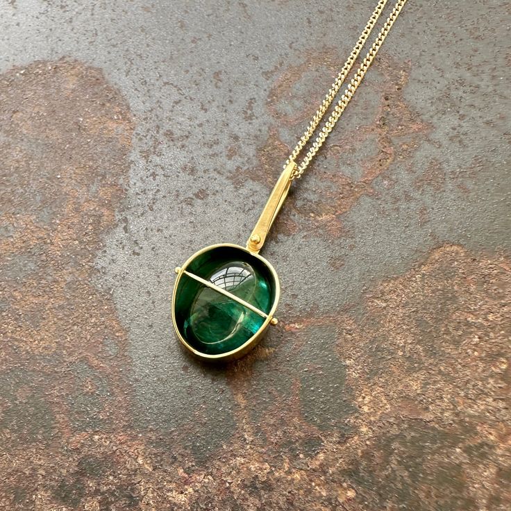 This necklace lives at The Phoenix in Washington D.C. Please contact Hilary before purchasing to ensure availability. A deep teal green tourmaline with light-refracting inclusions is Captured in 18k gold with Hilary's signature setting. A pendant that is perfect with your favorite white t-shirt or your best little black dress. One of a kind. 18k gold, tourmaline. 7/8 x 3/8 inch. This listing is for the pendant only. For a full necklace, choose from three elegant chains, here. Modern Green Necklace With Polished Finish, Modern Green Emerald Jewelry, Green Tourmaline Pendant Jewelry, Green Tourmaline Gemstone Necklace, Green Pendant Necklace With Bezel Setting, Gold Oval Tourmaline Necklace, Green Emerald Cabochon Necklaces, Green Emerald Cabochon Necklace, Handmade Green Tourmaline Necklaces