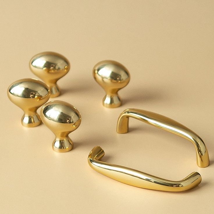 three shiny gold handles and pulls on a beige surface