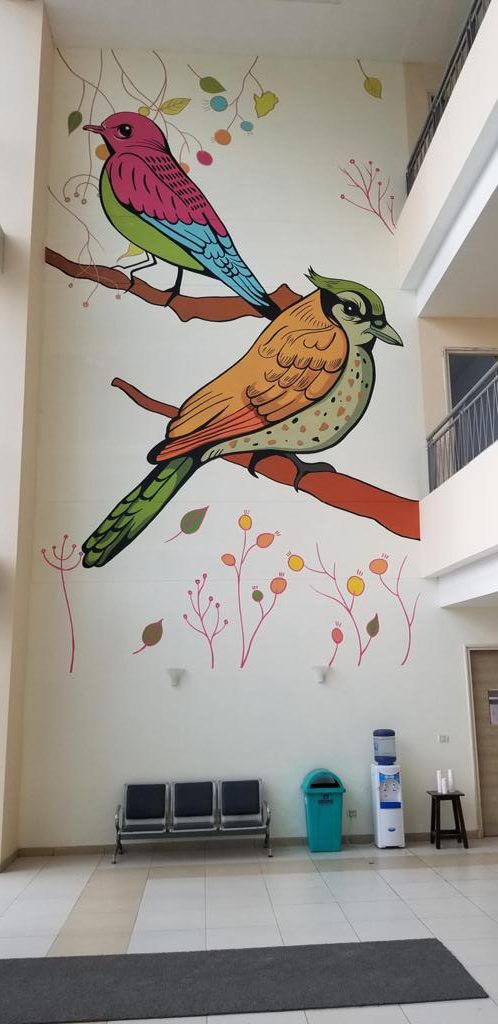 two birds sitting on top of a tree branch painted on the side of a building