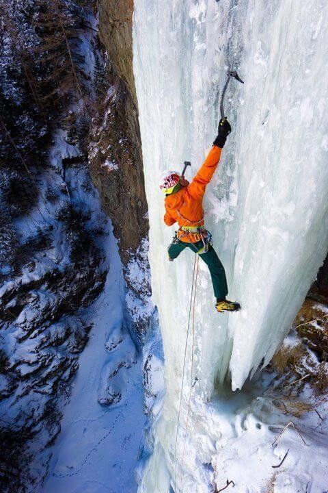 a man climbing up the side of a snow covered mountain