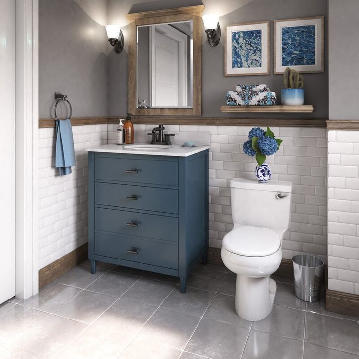 a white toilet sitting next to a bathroom sink under a mirror on top of a wooden cabinet