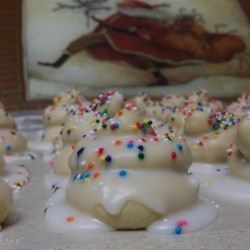 white frosted donuts with sprinkles on them sitting on a table