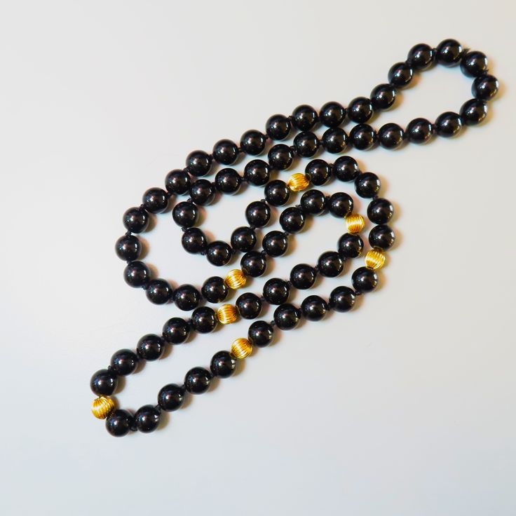 On offer is this beautiful Vintage 14kt. Yellow Gold Black Onyx Gemstone Necklace featuring large 10 mm Onyx Gems with large solid 14 karat yellow gold corrugated spacer beads. It measures a nice long 32 Inches in length with no clasp so it slips easily over your head. The lustrous and highly polished Onyx gems glow like glass and contrast nicely against the shiny 14 karat yellow gold beads. The necklace is hand knotted with black silk cord.  The 14kt yellow gold spacer beads measure a nice larg Elegant Black Jewelry With 8mm Beads, Luxury Black Pearl Necklace With Round Beads, Classic Black Round Beaded Jewelry, Gold Onyx Beaded Necklaces With Gemstone Beads, Elegant Black Jewelry With 108 Beads, Gold Onyx Gemstone Beaded Necklaces, Elegant Onyx Beaded Necklaces For Formal Occasions, Luxury Black Beaded Jewelry, Obsidian Necklace With Black Round Beads