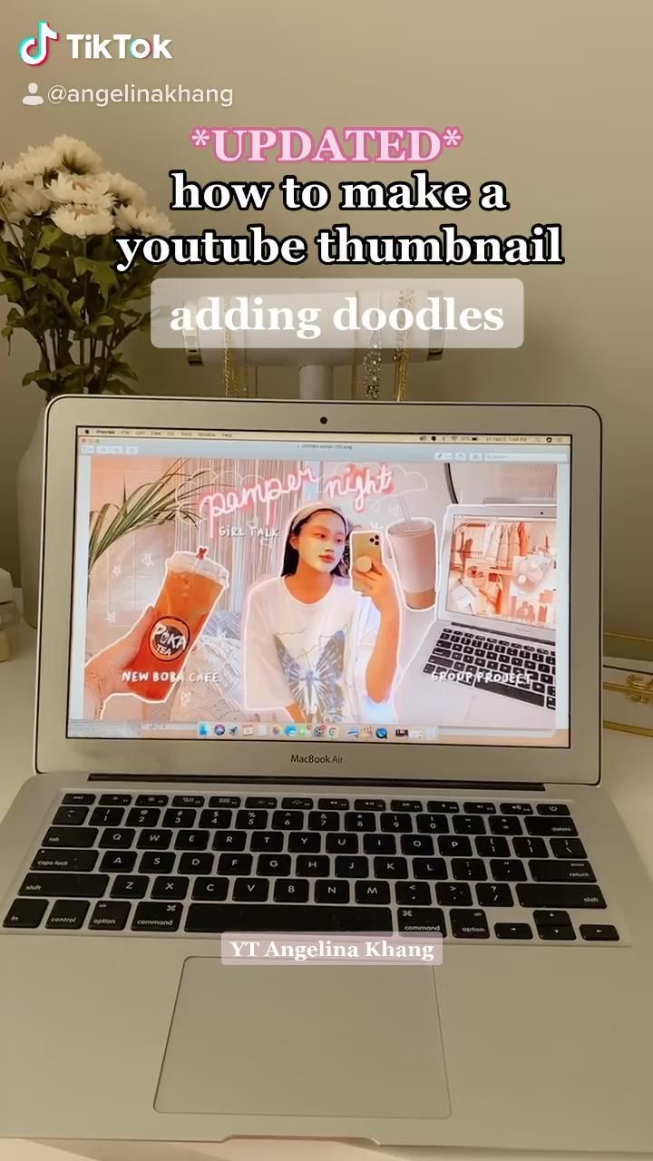 an open laptop computer sitting on top of a white desk next to a vase with flowers