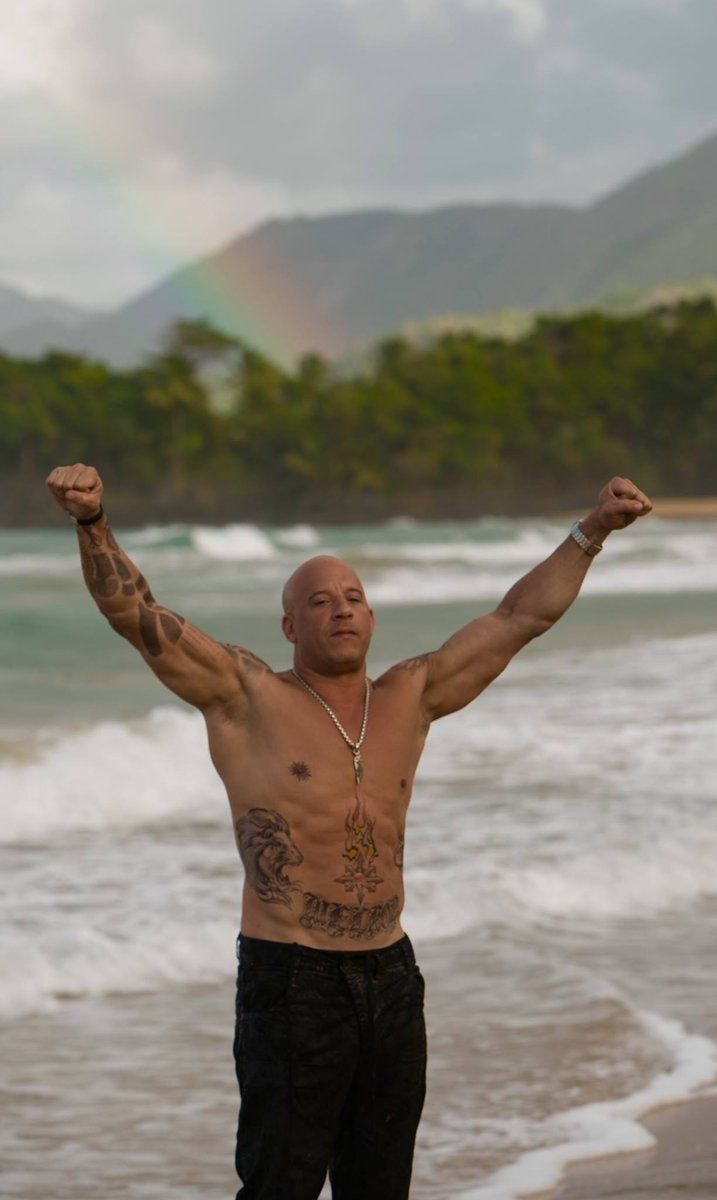 a man standing on top of a beach next to the ocean with his arms in the air