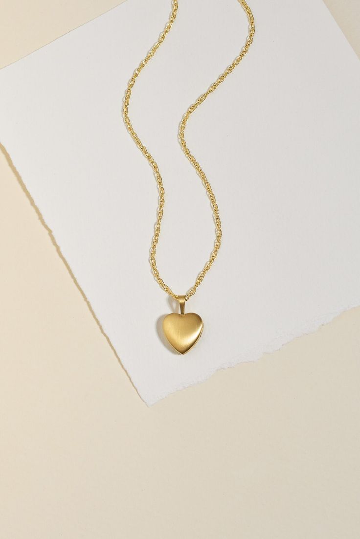 Experience the timeless beauty of our Heart Locket Necklace. Keep your loved ones close to your heart with this heirloom piece that holds precious memories. With a unique double-sided finish, choose between shiny gold or brushed matte. Strung on a sparkly double rope chain, this necklace makes a meaningful gift for Mother's Day or any special occasion. Size: Heart locket measures 18 x 12 mm Locket features a beautiful double sided finish - one side is shiny and the other is matte. You can remove Small Gold Heart Locket, Elegant Double Heart Charm Necklaces For Keepsake, Elegant Double Heart Charm Necklace Keepsake, Elegant Double Heart Locket Charm Necklaces, Elegant Heart Pendant Locket Necklace With Adjustable Chain, Matte Gold Brass Jewelry For Anniversary, Elegant Brass Jewelry With Heart Charm, Elegant Gold Heart Keepsake Necklace, Elegant Gold Heart Necklace For Keepsake