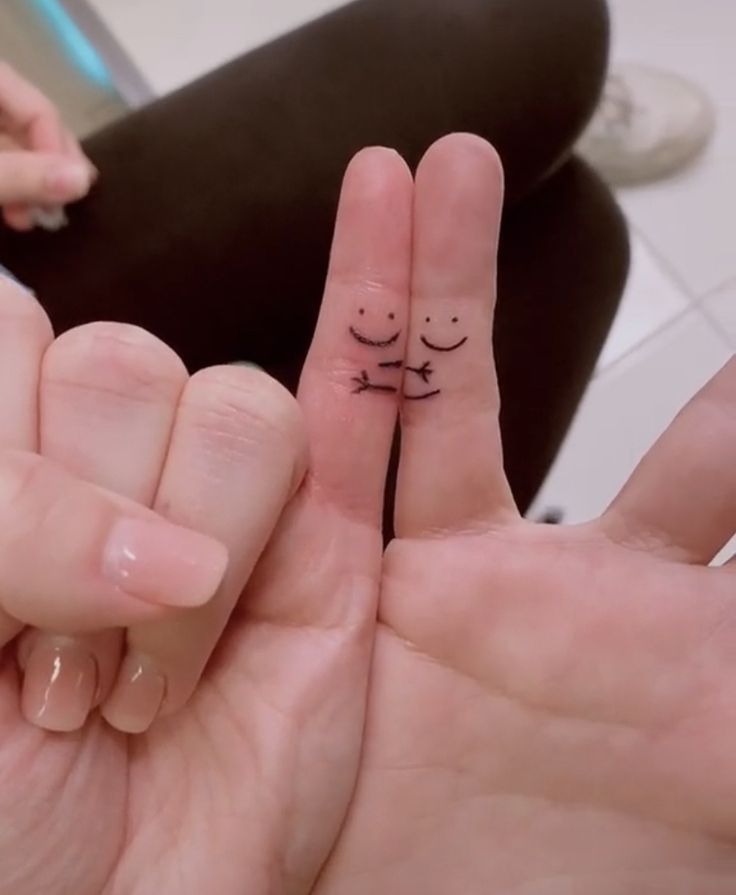 two fingers with faces drawn on them are in the middle of each other's fingers